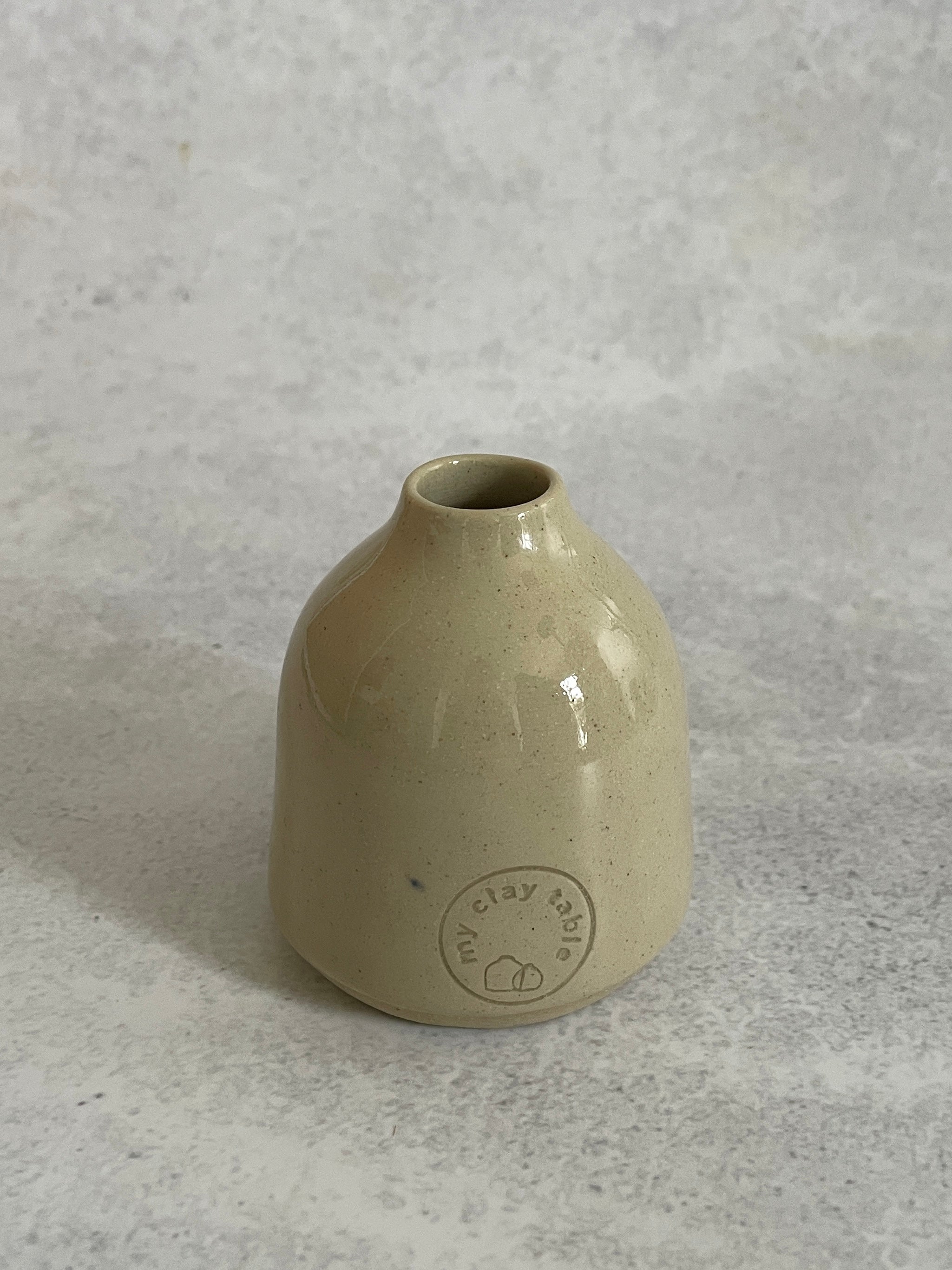 Beige ceramic vase with a logo on a gray background